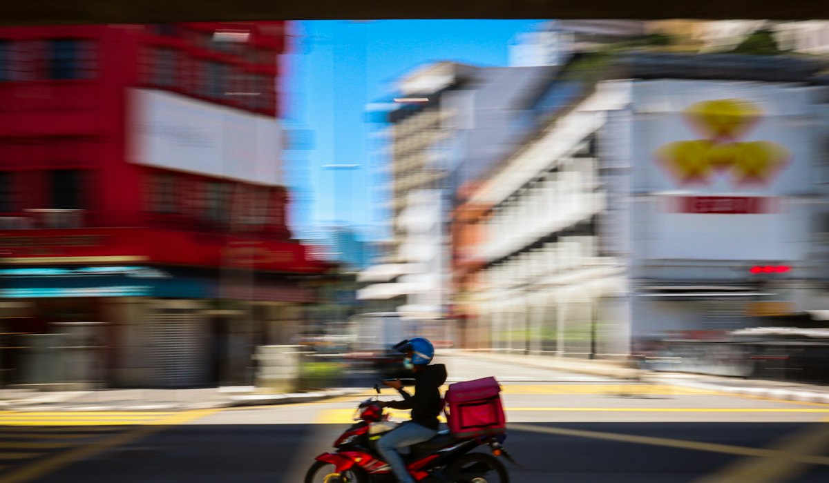 Entregador de moto na rua, dependente do aplicativo para trabalhar